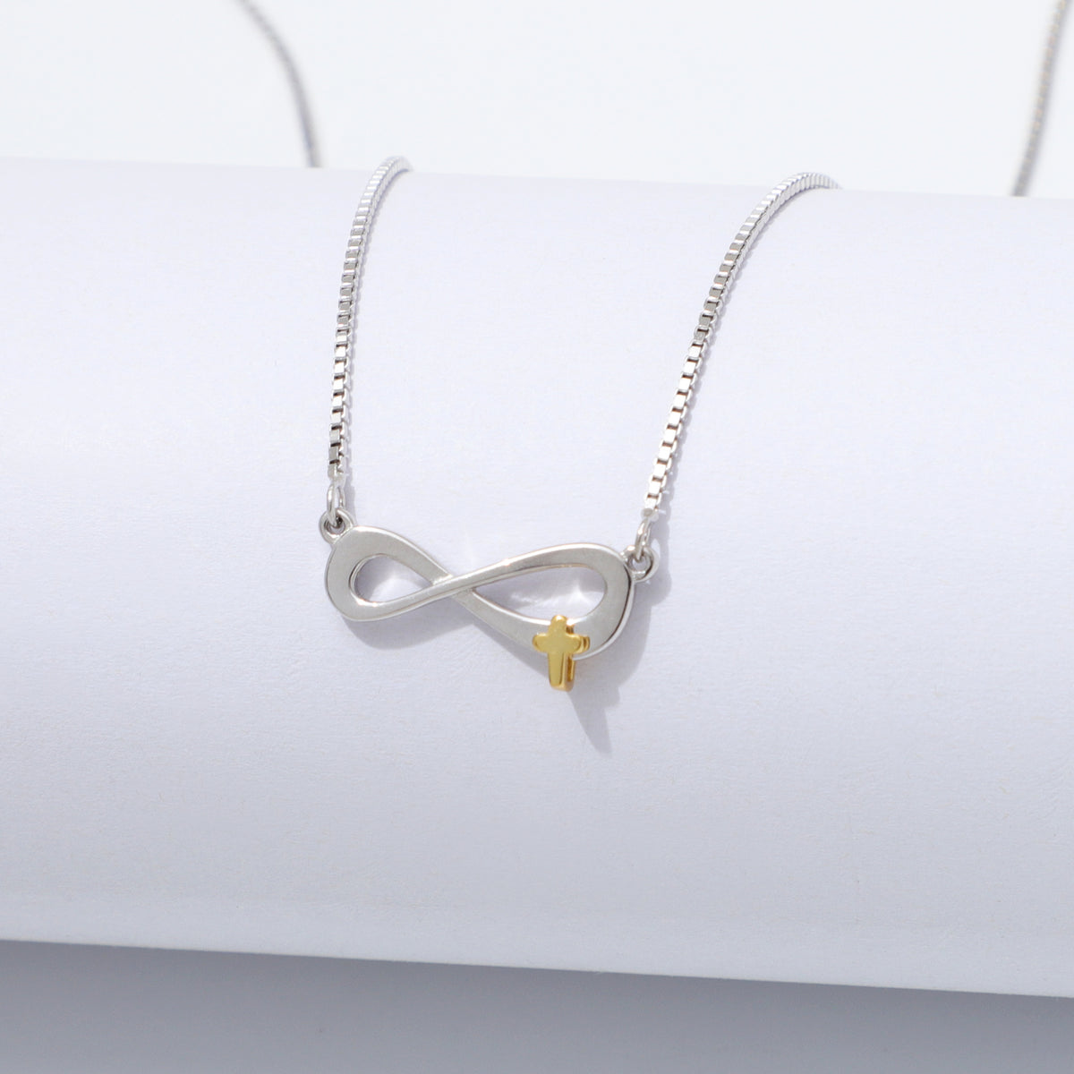 Silver 925 Sterling infinity necklace with a gold cross pendant on a white background