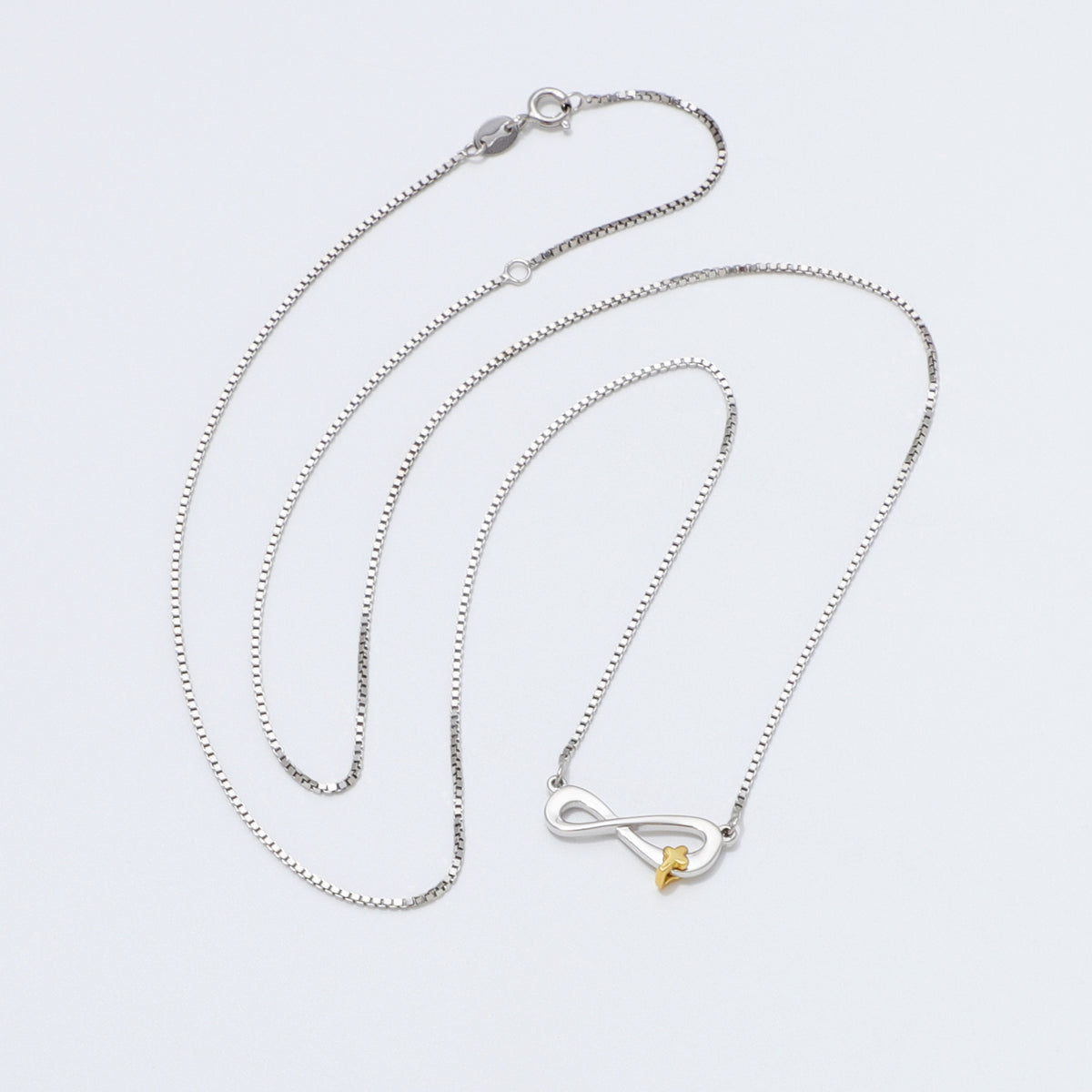 Silver 925 Sterling infinity necklace with a gold cross pendant on a white background