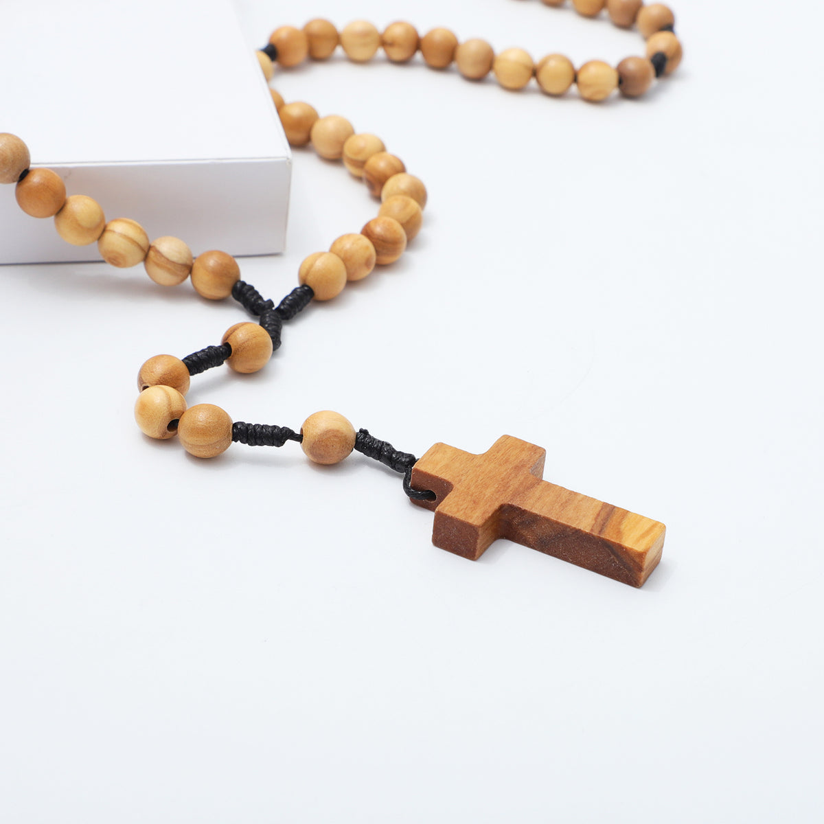 Close-up of the olive wood cross and 8mm rosary beads on black knotted cord
