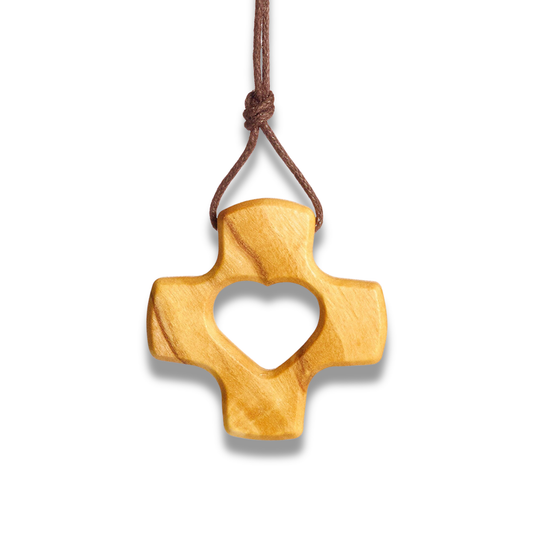 A carved wooden cross pendant with a heart-shaped cutout in the center, hanging from a brown cord on a plain white background.
