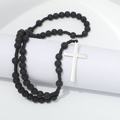 Lava stone prayer rosary and plain metal cross draped over white blocks