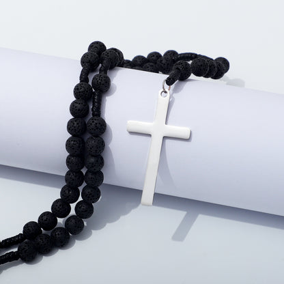 Lava stone rosary necklace and plain metal cross draped over a white block