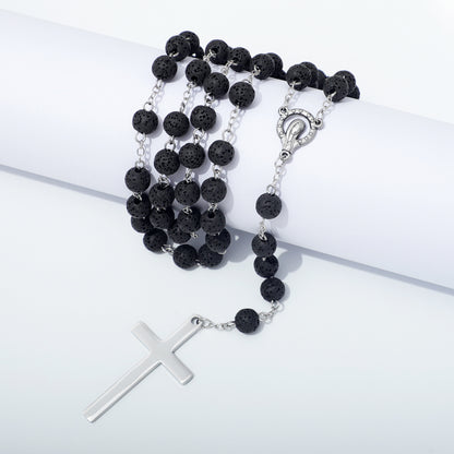 Lava stone rosary and metal cross draped over a white block