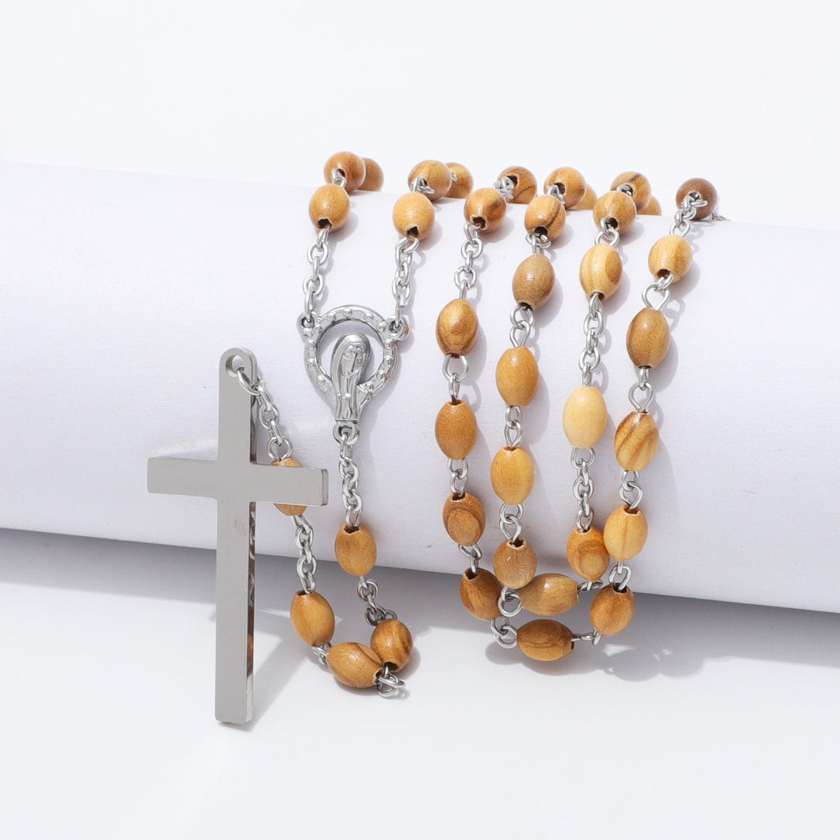 Oval olive wood rosary with Virgin Mary centerpiece draped over a white block