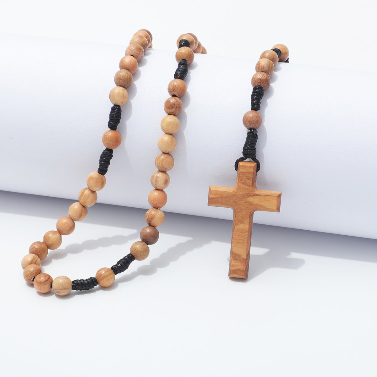 A wooden bead rosary necklace with a matching wooden cross pendant, displayed on a clean white background.