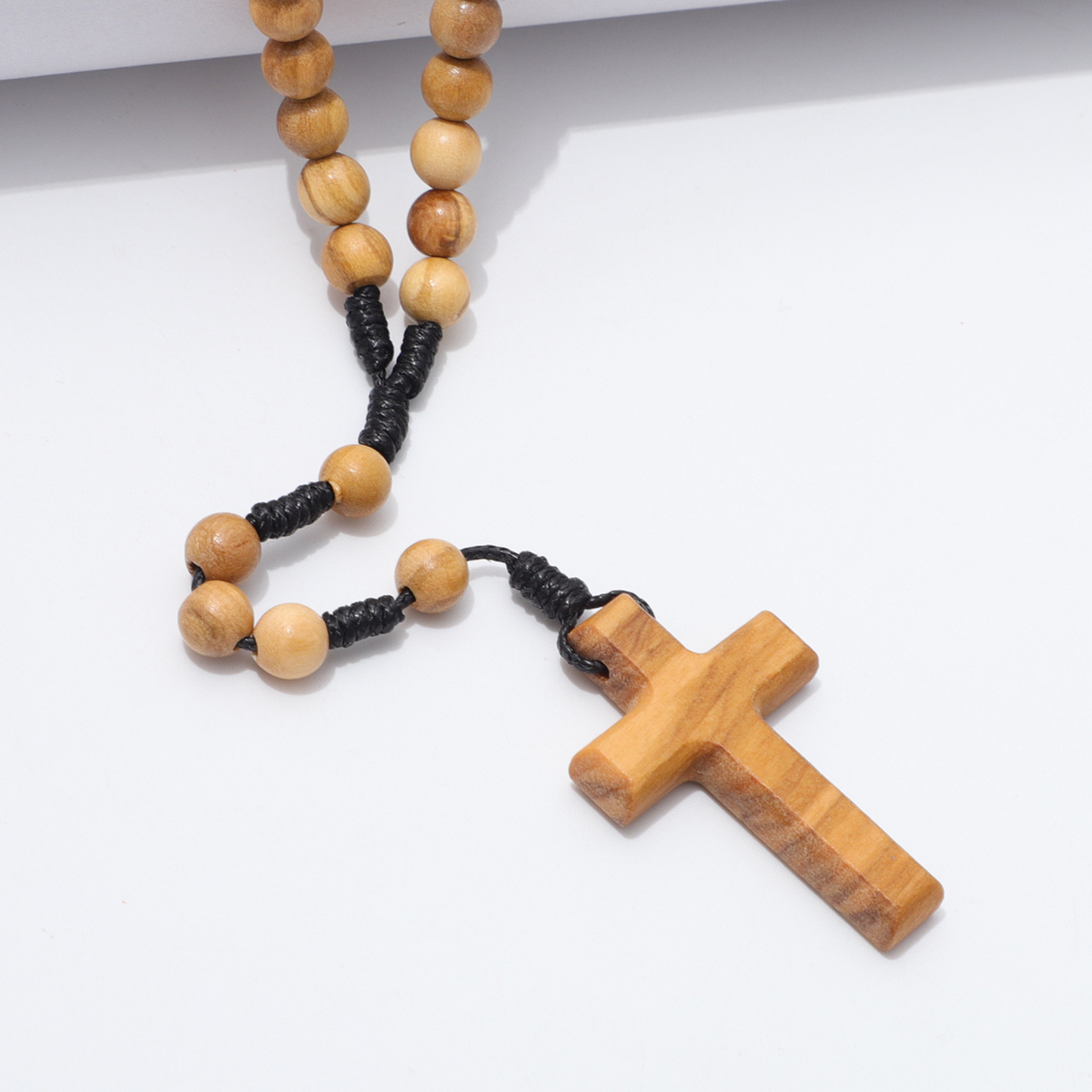 Close view of the olive wood cross and small beads on knotted cord