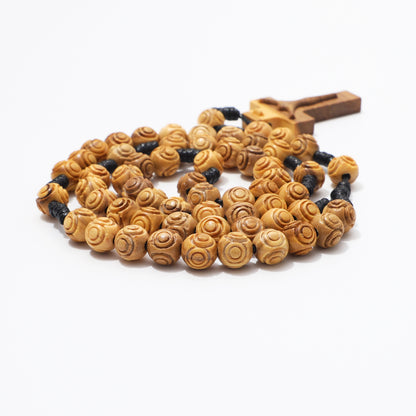 Side view of coiled 8mm engraved olive wood rosary beads with carved crucifix