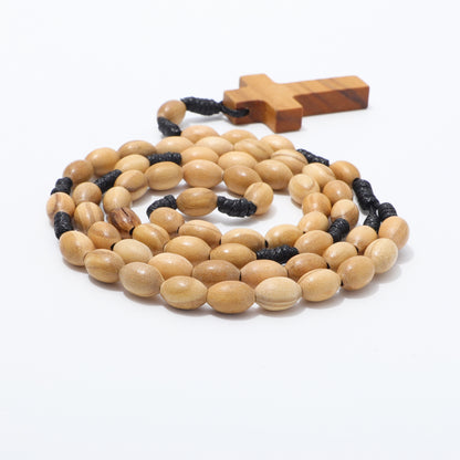 Side view of coiled oval olive wood beads on black knotted cord with a wooden cross