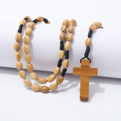Oval olive wood rosary beads and wooden cross draped over a white block