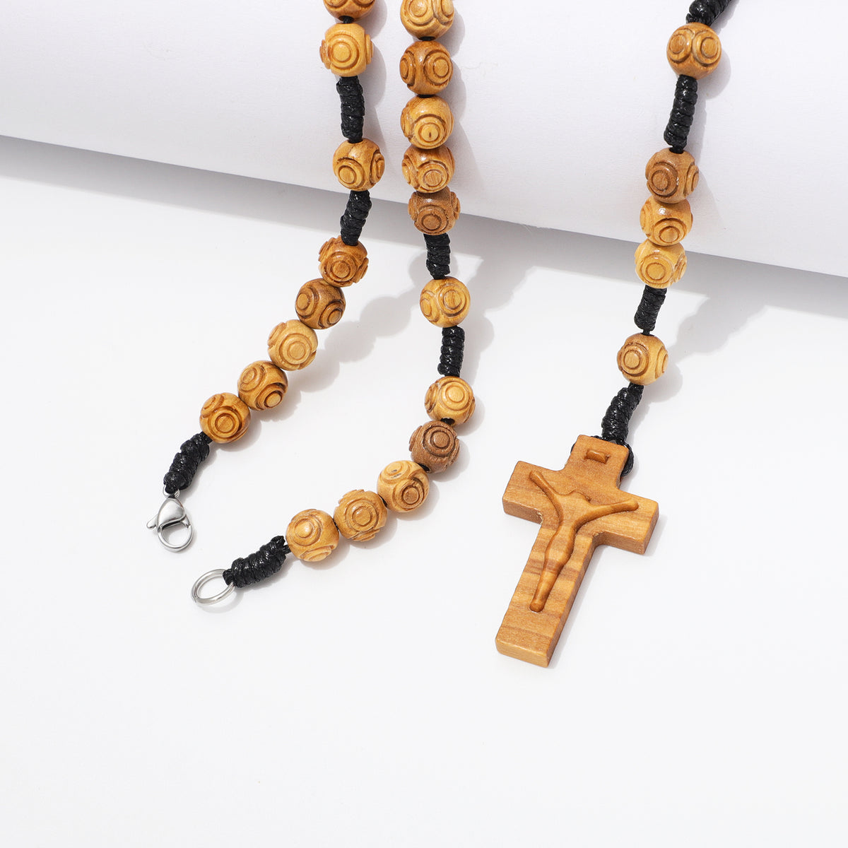 Engraved olive wood rosary necklace with 8mm beads and crucifix draped over a white block