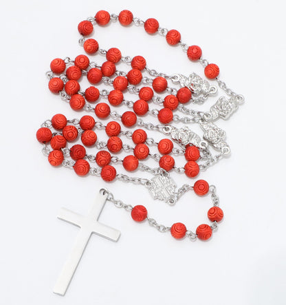 Engraved red bead rosary arranged beside a polished cross and Jerusalem Cross centerpiece