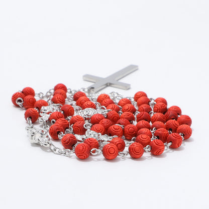 Close view of engraved circular patterns on red rosary beads