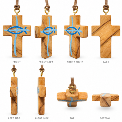A wooden Christian cross pendant with a natural warm brown wood grain, featuring a blue Ichthys fish symbol and a vertical light blue cross. The cross hangs from a brown cord with a gold-colored metal ring, shown against a plain white background. Shown from all sides.