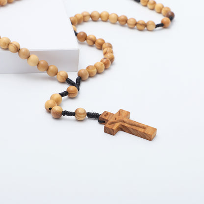 Close up of the carved olive wood crucifix and round beads on black knotted cord