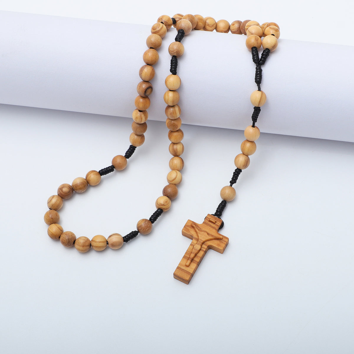 Olive wood beads and carved crucifix draped over a white block