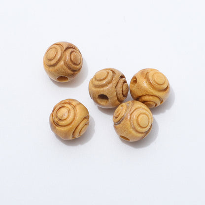 Close up of five loose 8mm engraved olive wood beads showing circular patterns