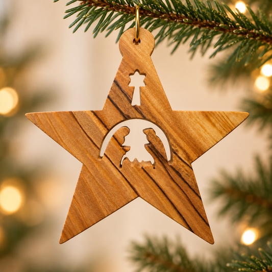 Olive wood Guiding Star ornament with a Holy Family cutout, hanging from a fir branch against warm Christmas lights.